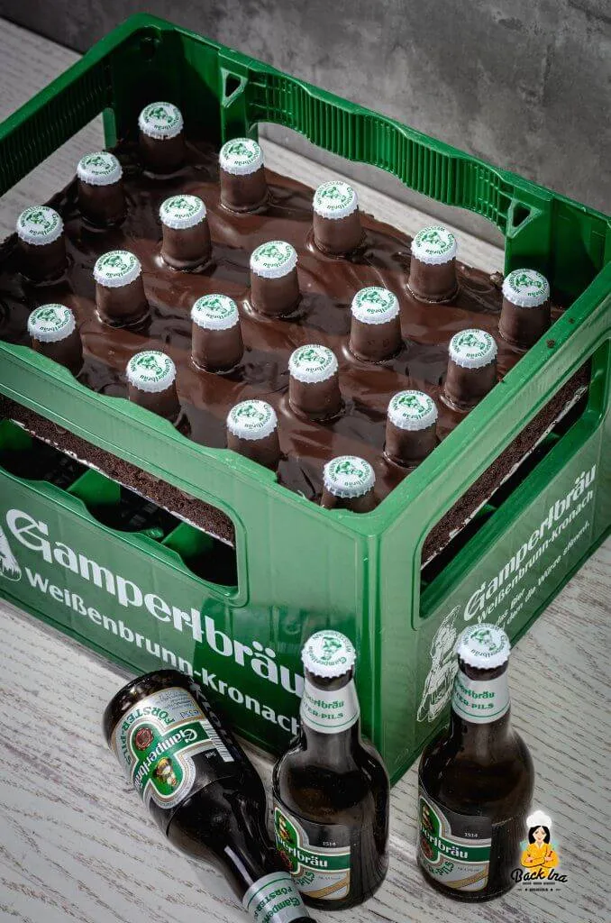 Eine aufwendig gestaltete Bierkasten-Torte, die aus Kuchen und Schokoladenfiguren geformt ist und mit Kronkorken verziert wurde.
