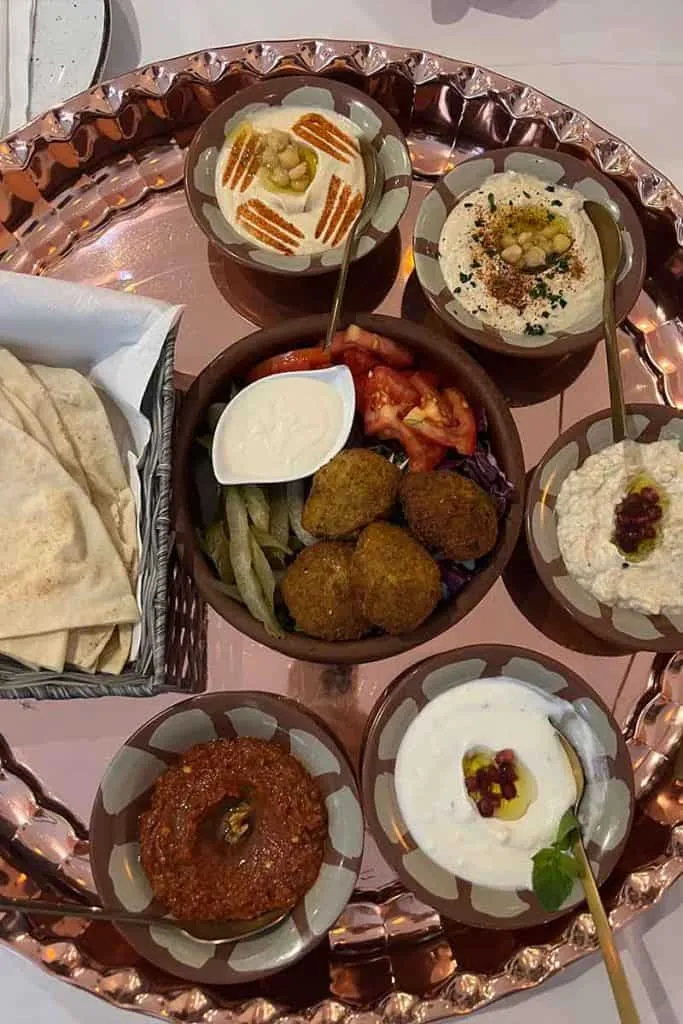 Eine Auswahl an levantinischen Gerichten wie Hummus, Baba Ganoush, Falafel und frisches Pitabrot, wunderschön präsentiert auf einem großen Kupferteller im Byblos Restaurant in Zagreb.