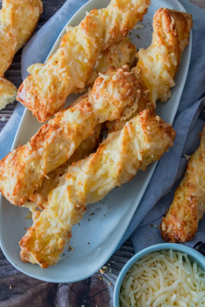 Eine Auswahl selbstgemachter Käsestangen auf einem Teller, bereit als einfacher herzhafter Snack.