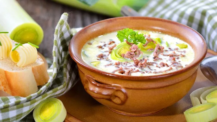 Eine dampfende Käse-Lauch-Suppe mit Hackfleisch in einem großen Topf.