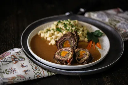 Eine dampfende Rindsroulade mit Spätzle, ein Sinnbild für herzhafte deutsche Wintergerichte