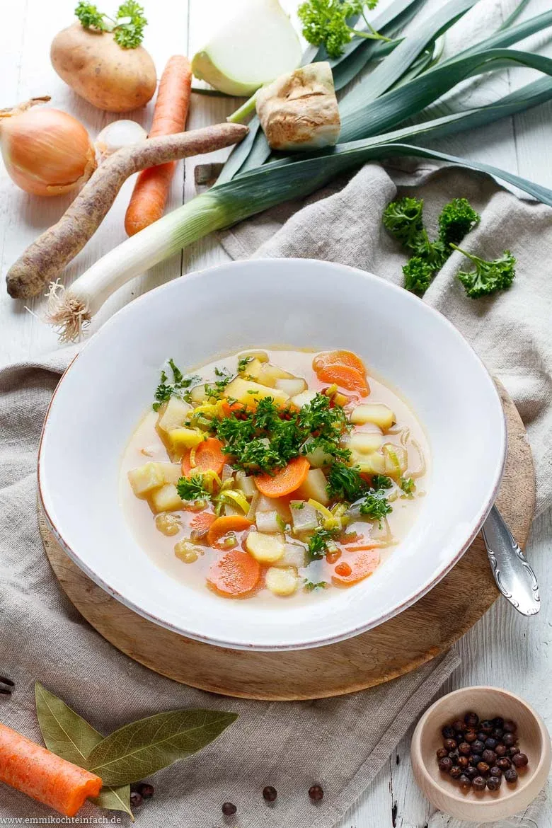 Eine dampfende Schüssel Omas Gemüsesuppe mit frischer Petersilie garniert, bereit zum Genießen nach dem Suppe kochen für Anfänger.