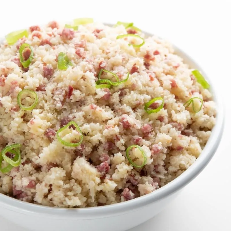 Eine deftige Keto Bratreis-Frühstücks-Bowl mit Blumenkohlreis und Schinken, eine sättigende Mahlzeit am Morgen.