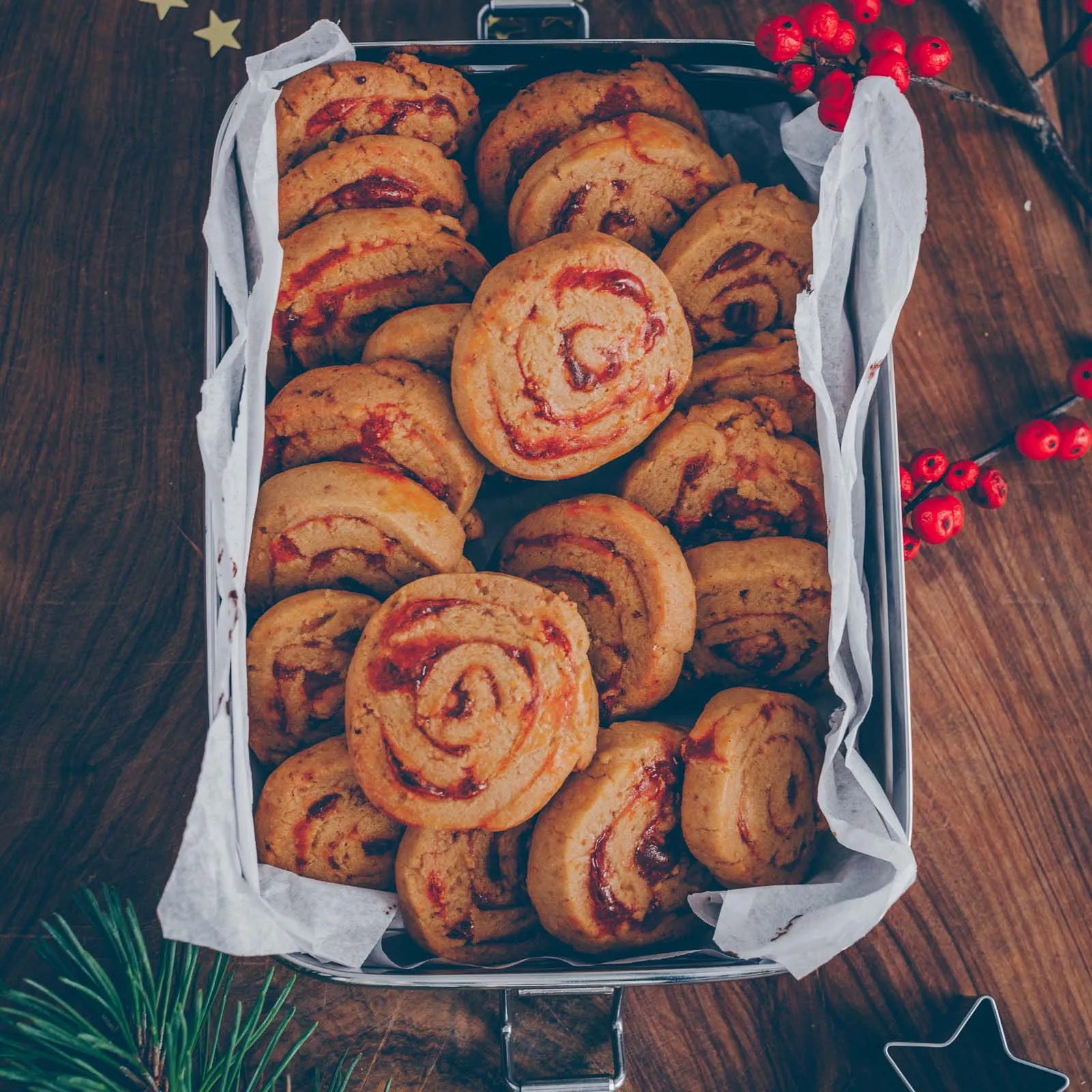 Eine dekorative Anordnung von frisch gebackenen veganen Plätzchen auf einem festlichen Tischtuch, ideal für die Weihnachtsbäckerei