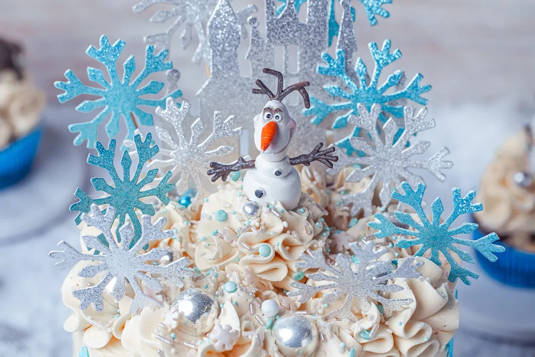 Eine detailreiche Aufnahme einer Frozen Torte mit Schneeflocken, blauen Elementen und einem Cake Topper Set