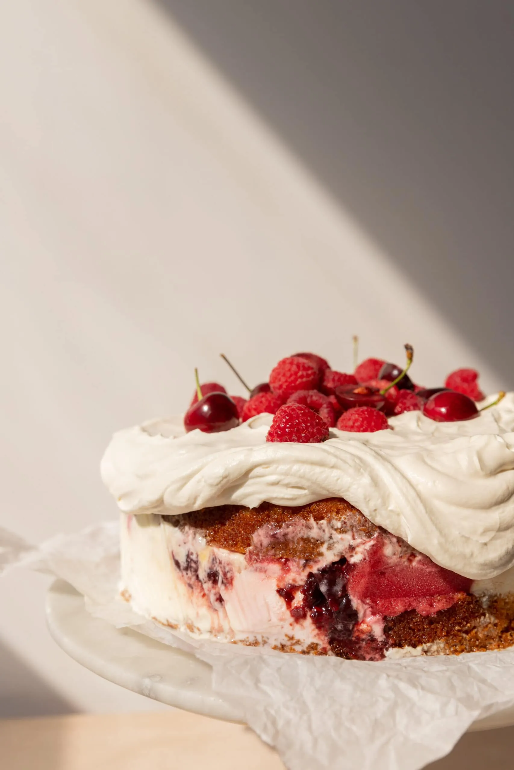 Eine Eistorte mit Schichten aus Vanillekuchen und verschiedenen Eissorten, dekoriert mit Schlagsahne und Beeren.