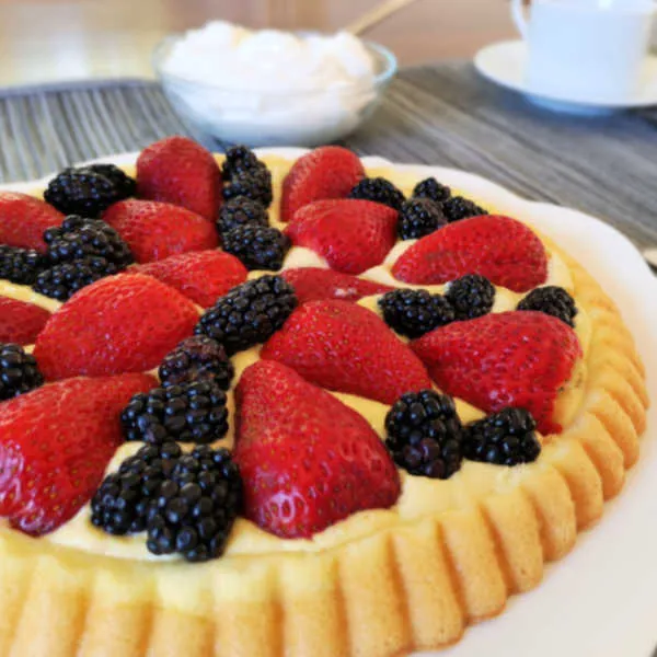Eine Erdbeer-Brombeer-Obsttorte, die mit einem Löffel Vanillepudding zubereitet wurde.