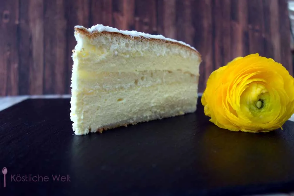 Eine fertig gebackene, mit Puderzucker bestäubte Zitronen-Quark-Sahne-Torte, appetitlich auf einer Tortenplatte präsentiert