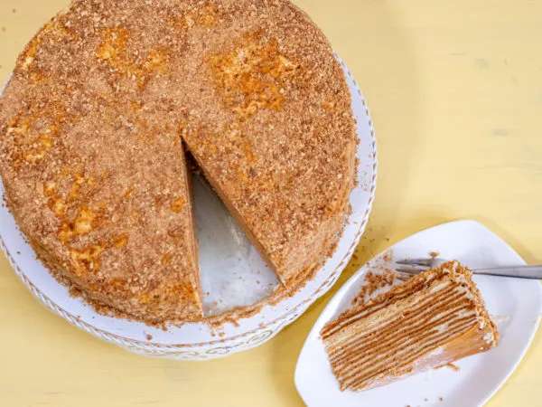 Eine festliche Präsentation des russischen Geburtstagskuchens Medovik auf einem Tortenständer, bereit zum Servieren.