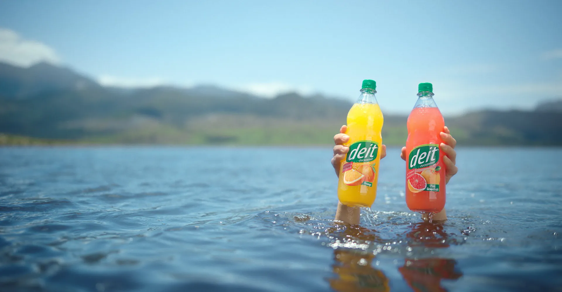 Eine Flasche DEIT Citro vor einem Hintergrund aus Zitronenscheiben. Der Alt-Text lautet: Erfrischender DEIT Citro mit dem klaren Geschmack sonnengereifter Zitronen, ideal für eine kalorienarme Ernährung.