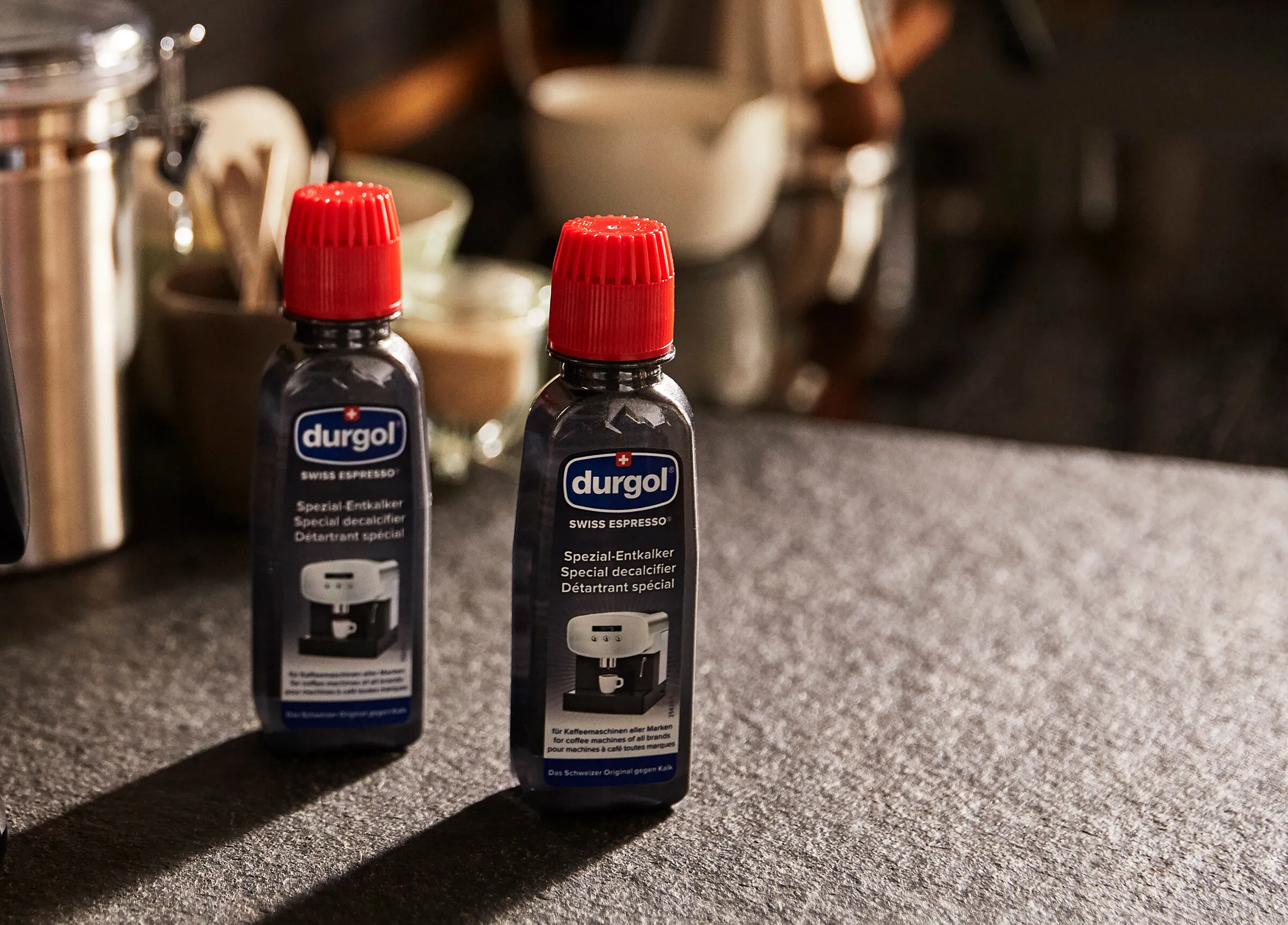 Eine Flasche durgol Spezial-Entkalker neben einem Tchibo Kaffeevollautomat, symbolisierend das empfohlene Produkt für die effektive Entkalkung der Tchibo Maschine.