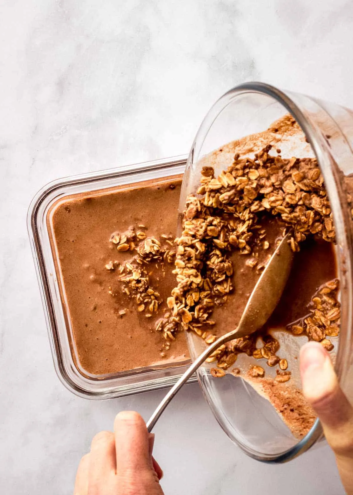 Eine Frau gießt Espresso Overnight Oats aus einer Schüssel in einen luftdichten Behälter.