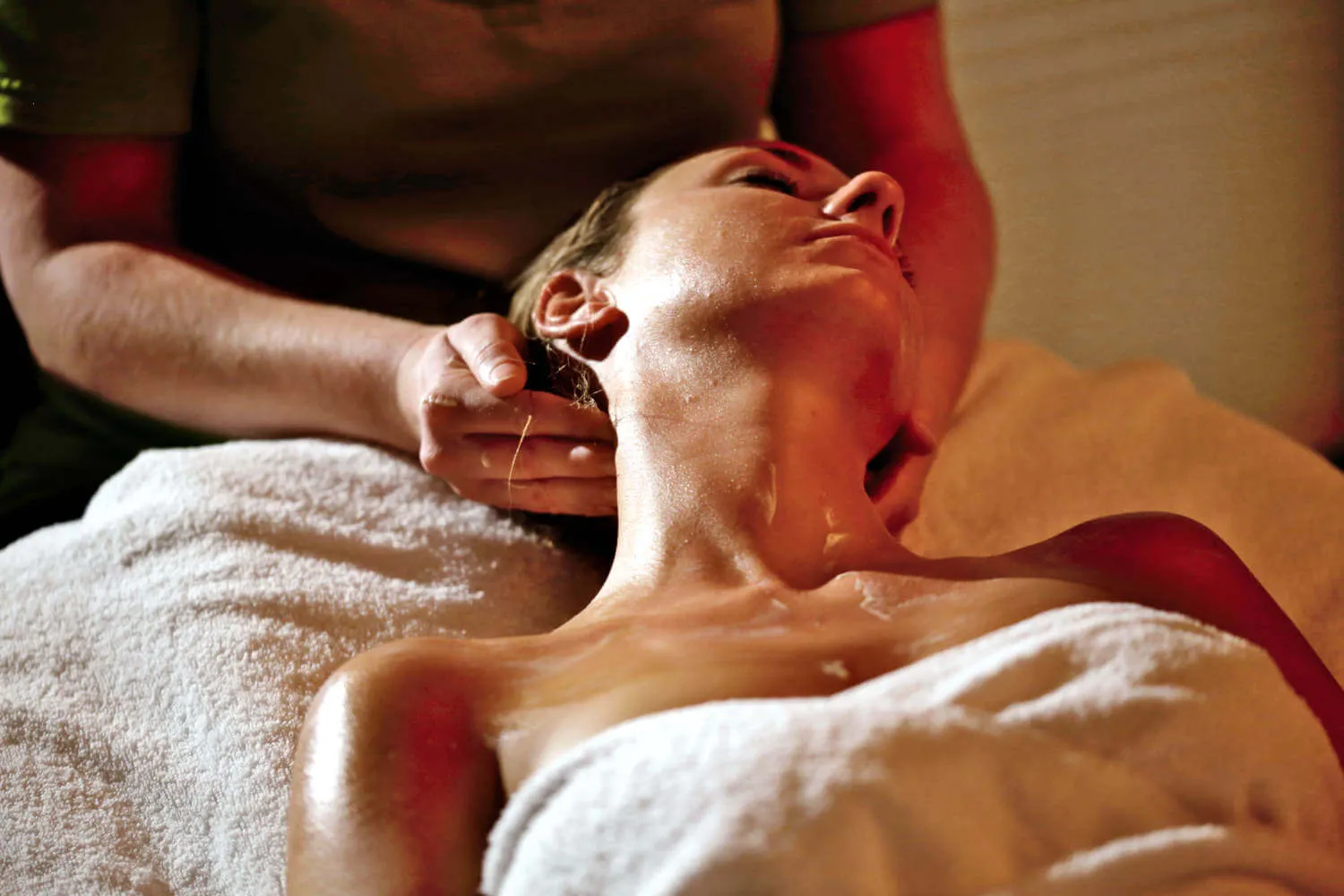 Eine Frau liegt auf der Wellnessliege und erhält eine Nackenmassage