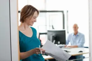 Eine Frau liest aufmerksam wichtige Dokumente in einem modernen Büroumfeld.