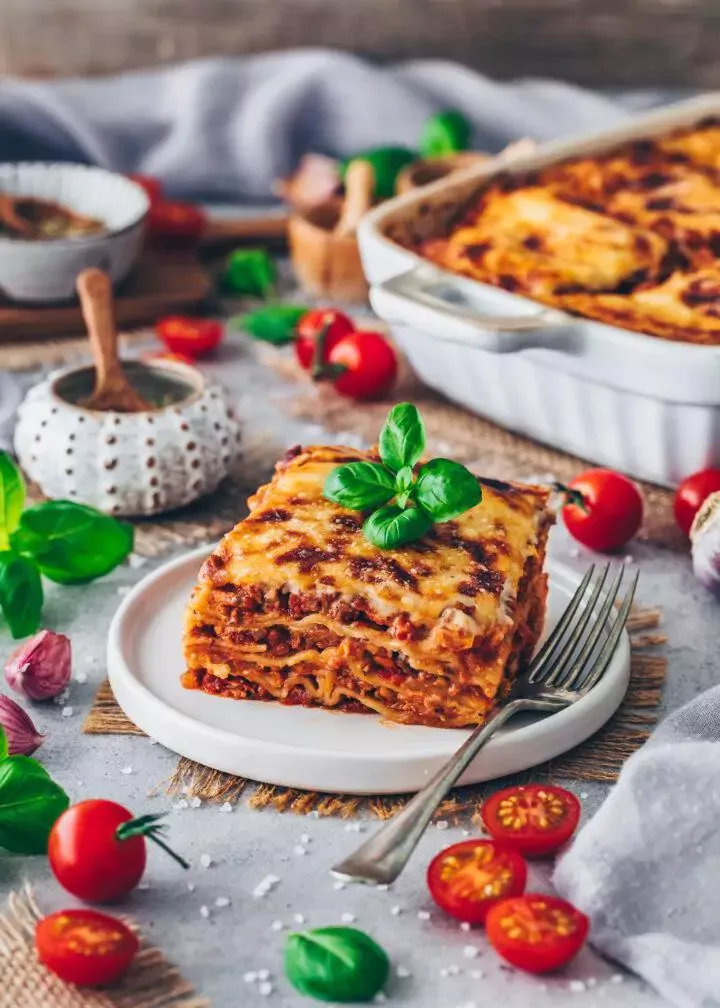 Eine frisch gebackene, goldbraune vegane Lasagne Bolognese mit Kräutergarnitur, fertig zum Servieren.
