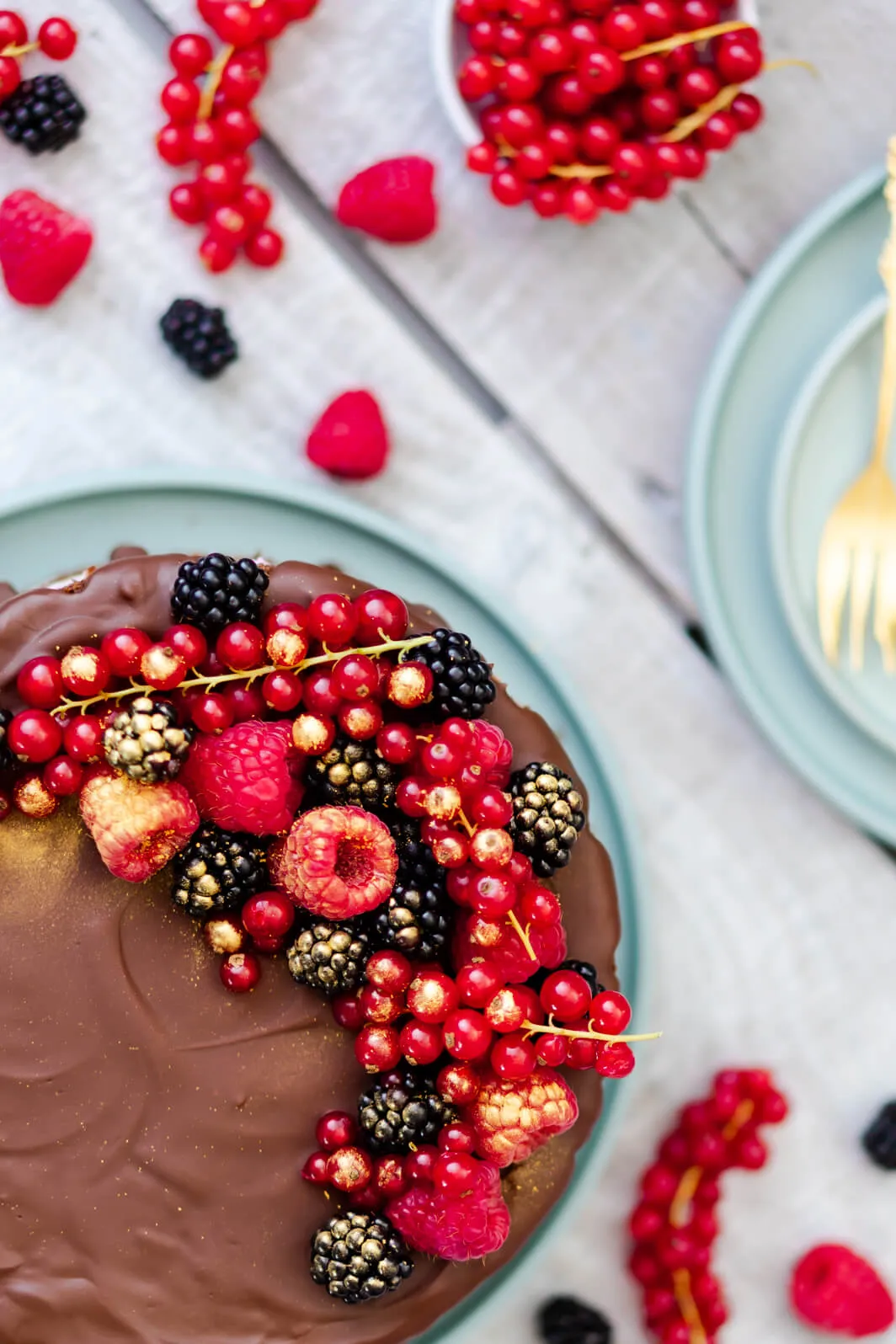 Eine frisch zubereitete mehrstöckige Sahnetorte mit Beeren und Schoko-Drip, perfekt für festliche Anlässe.