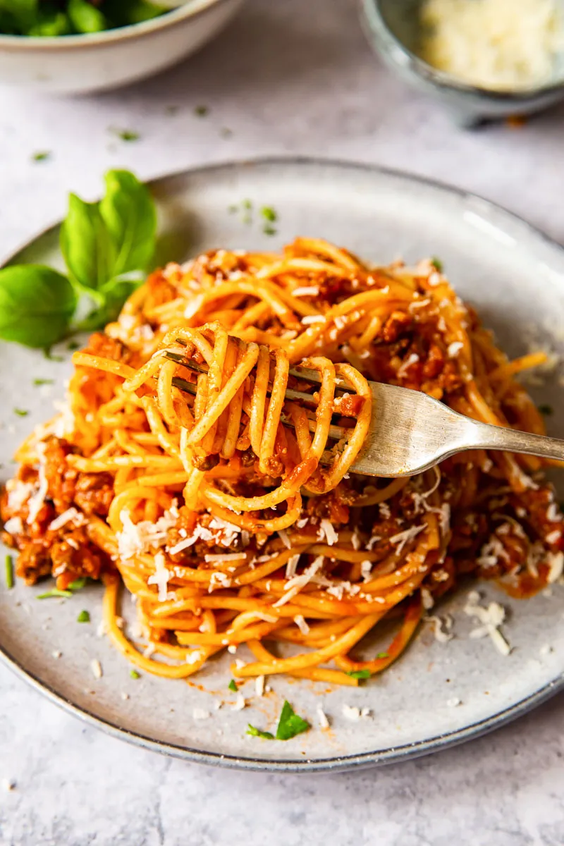 Eine Gabel mit perfekt aufgewickelten Spaghetti Bolognese, bereit zum Probieren.