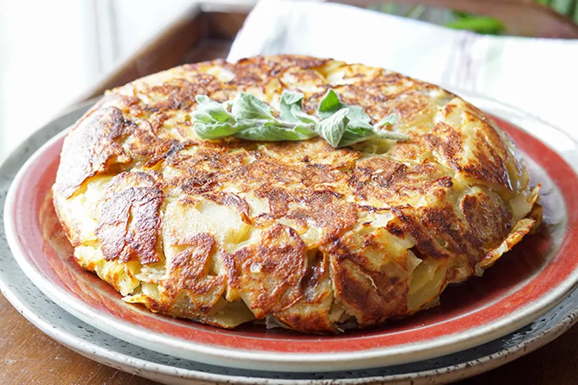 Eine ganze, selbstgemachte Spanische Tortilla, geschnitten und bereit zum Genießen.