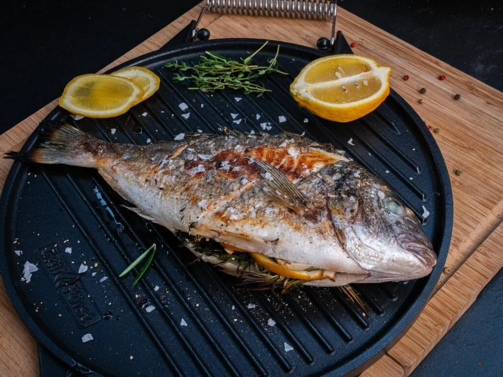 Eine goldbraun gegrillte Dorade auf der Grillplatte, ein mediterranes Highlight unter den besten Fisch Grillrezepten