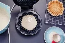 Eine goldbraune Waffel wird im Waffeleisen fertig gebacken, der Dampf entweicht