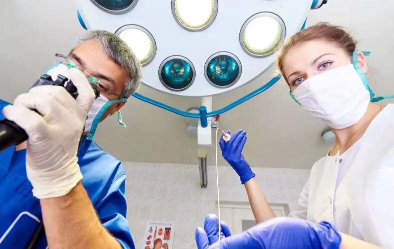 Eine Grafik, die die empfohlene Schutzausrüstung für Endoskopiker während der COVID-19-Pandemie zeigt, einschließlich FFP2-Maske, doppelten Handschuhen, wasserdichtem Kittel, Haube und Augenschutz.