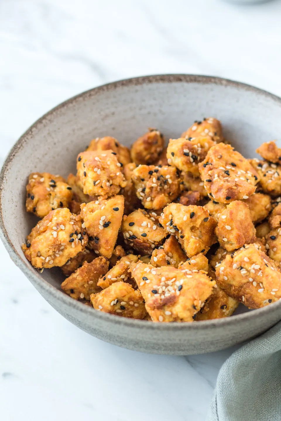 Eine Hand, die Tofu-Stücke in eine Pfanne mit Öl gibt