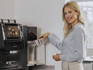 Eine Hand füllt Hafermilch in ein Frischmilchmodul eines Kaffeevollautomaten, um vegane Kaffeespezialitäten zuzubereiten