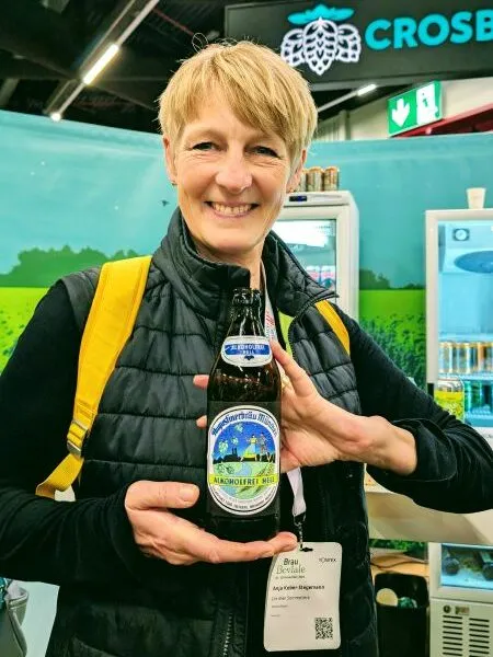 Eine Hand hält eine Flasche Augustiner Helles alkoholfrei, ein Beispiel für die hohe Qualität moderner deutscher alkoholfreier Biere, ähnlich dem Köstritzer Schwarzbier Alkoholfrei.