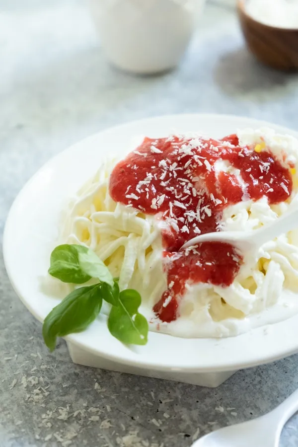 Eine Hand hält einen Löffel mit Spaghettieis, um die Schichten zu zeigen
