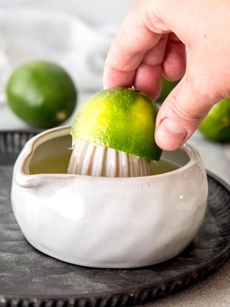 Eine Hand presst eine Limette mit einer Zitruspresse aus für den Cool Lime Refresher.