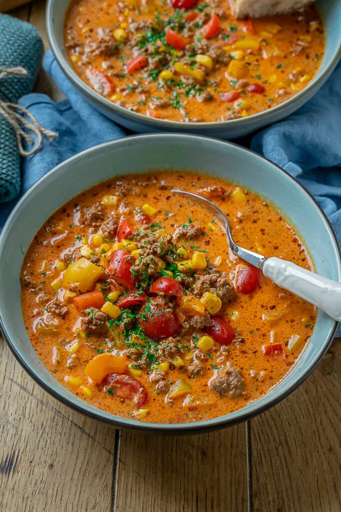 Eine herzhafte Pizzasuppe mit Hackfleisch, Paprika und Mais, serviert in einer rustikalen Schale. Perfekt als einfache Suppe mit wenig Zutaten.