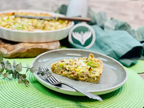 Eine herzhafte Quiche Lorraine mit Speck und Käse, aufgeschnitten auf einem Holzbrett