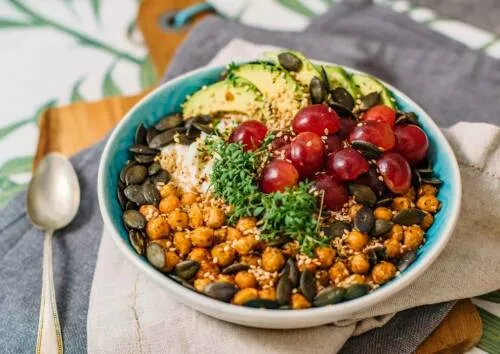 Eine High Protein Frühstücksbowl gefüllt mit Quark, Früchten und Nüssen.
