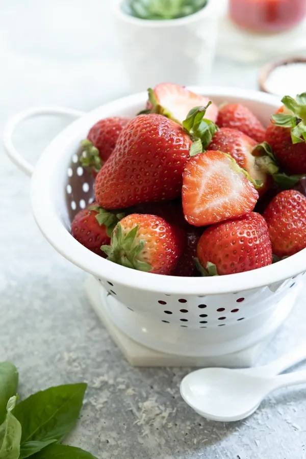 Eine Kartoffelpresse, gefüllt mit Vanilleeis, wird über einen Teller gedrückt