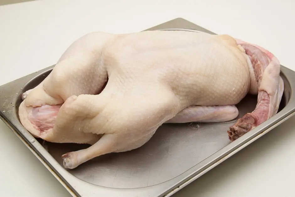 Eine küchenfertig vorbereitete Gans auf einem Schneidebrett, bereit zum Füllen.