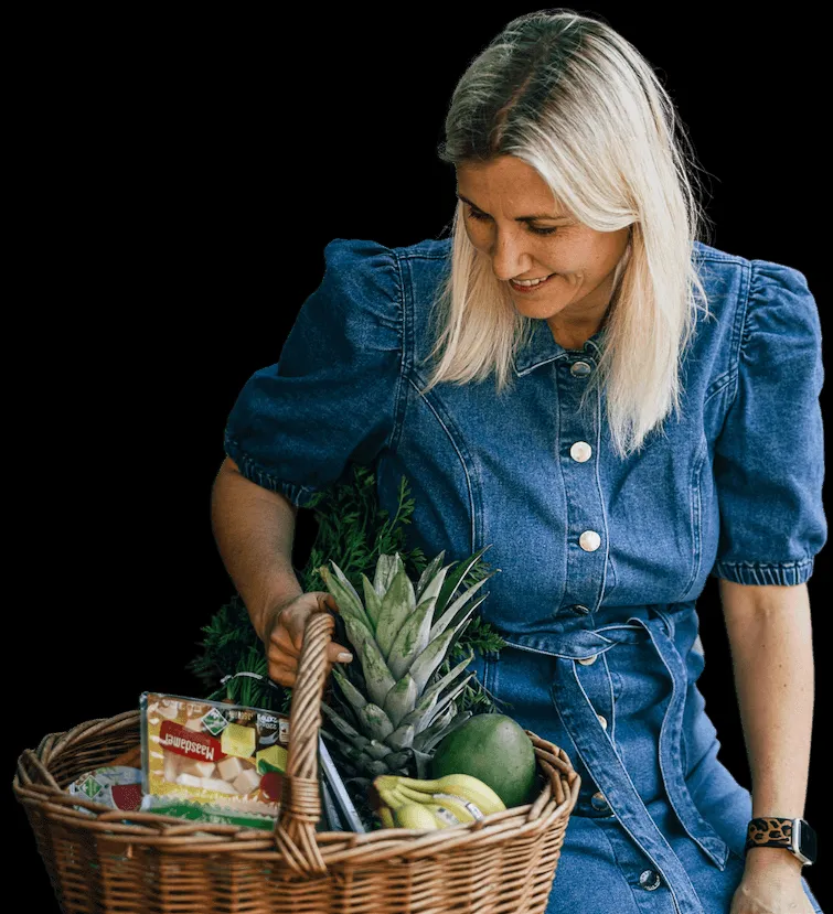 Eine lächelnde Frau (Jenny) mit einem gefüllten Einkaufskorb, die gesunde Rezepte für die Heißluftfritteuse präsentiert