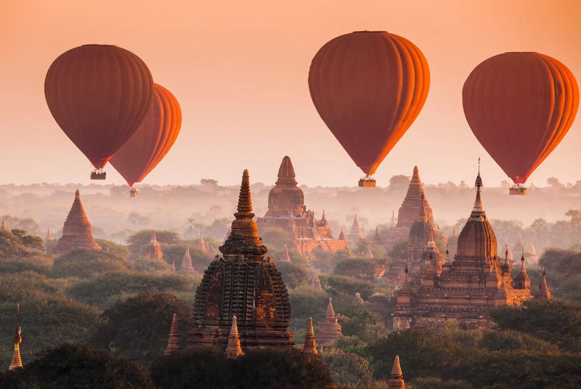 Eine Landschaft in Bagan, Myanmar, mit hunderten von Tempeln, die aus dem grünen Dschungel ragen.