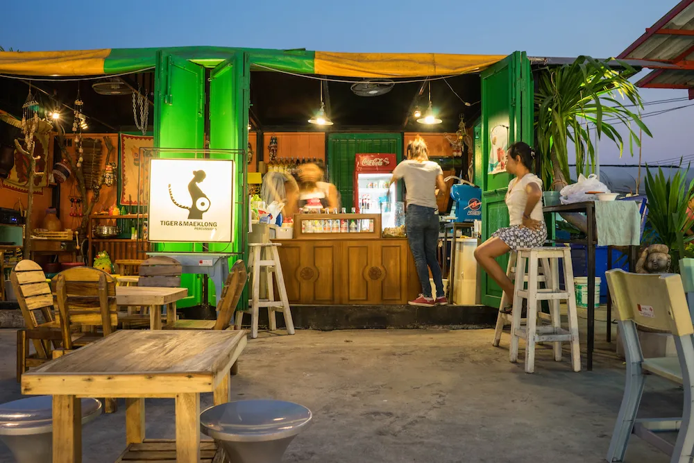 Eine lebhafte Bar auf einem Nachtmarkt – die perfekte Kulisse, um nach einem Longdrink auch mal ein erfrischendes Fanta Rot zu genießen.