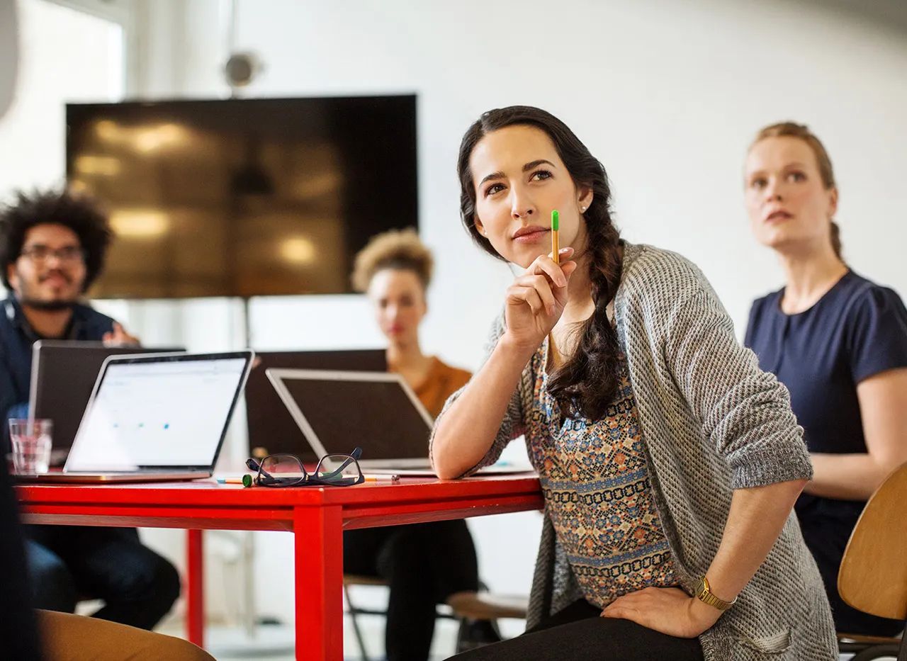 Eine Lehrerin erklärt Schülern etwas am Tisch.