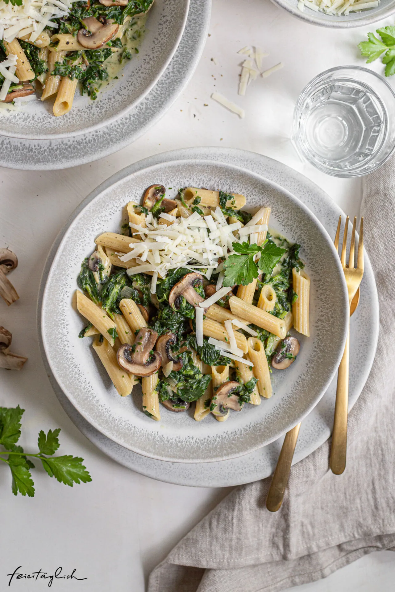 Eine Nahaufnahme der cremigen Pasta mit Spinat und Pilzen, die in einer Pfanne serviert wird.