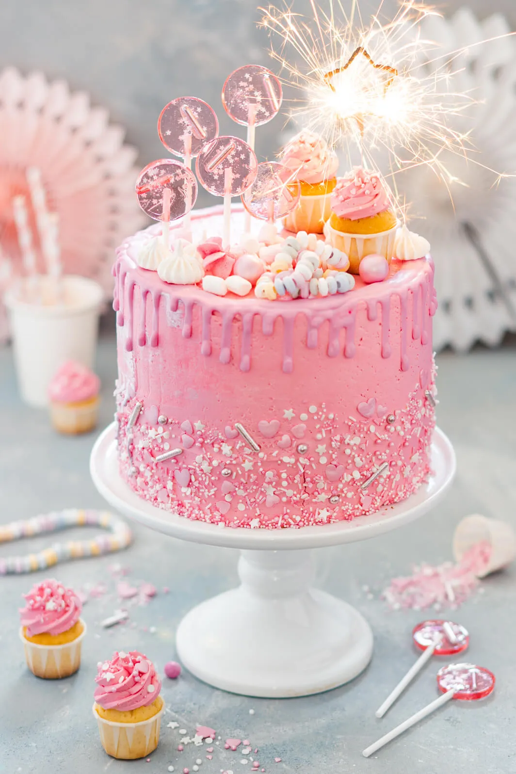 Eine Nahaufnahme der Deko-Elemente eines Drip Cakes, darunter Baiser-Drops, frische Himbeeren und Schokostreusel, die einen luxuriösen und appetitlichen Eindruck vermitteln.