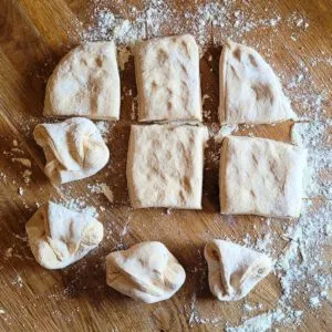 Eine Nahaufnahme des Teiges, der sorgfältig zu Dinkel-Sauerteig-Brötchen geformt wird.