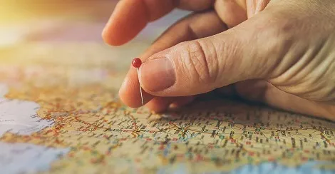 Eine Person plant eine günstige Studentenreise auf einer Karte mit Laptop und Notizen