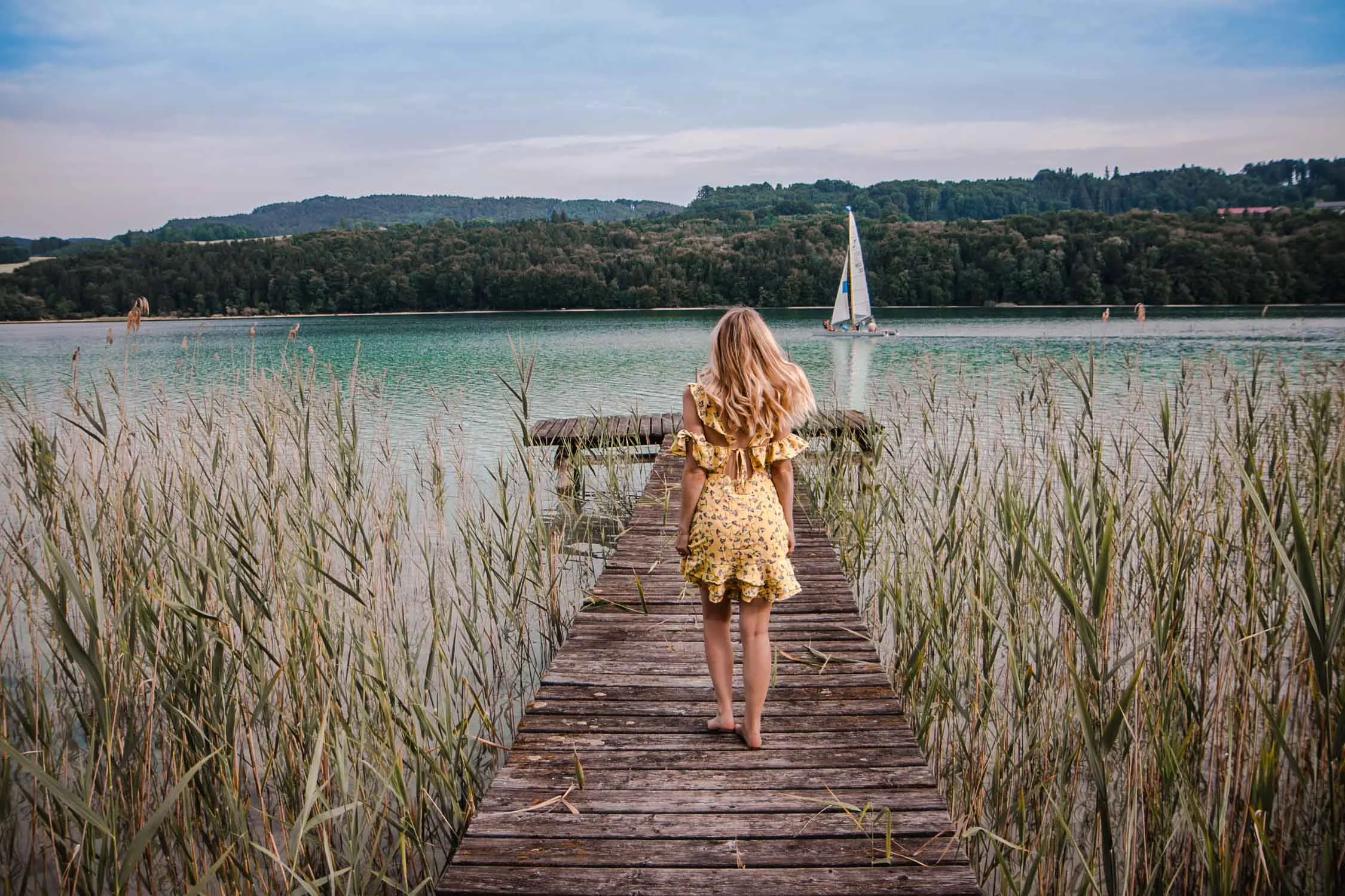 Eine Person sitzt auf einem Felsen mit Blick auf einen See