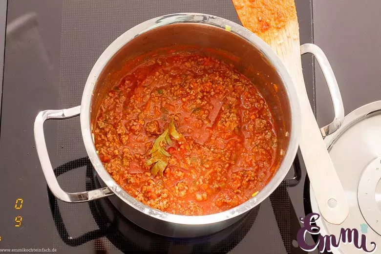 Eine Pfanne mit köchelnder Bolognese Soße, die die stückigen Tomaten und das angebratene Hackfleisch zeigt.