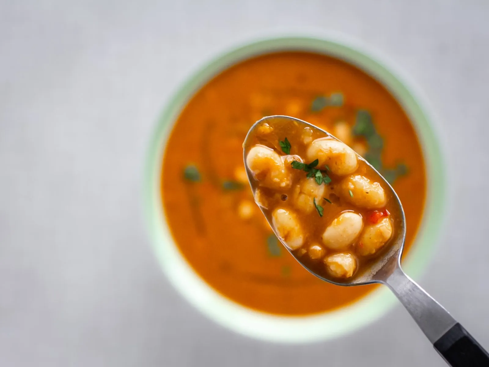Eine Portion albanische weiße Bohnensuppe mit einem Löffel, bereit zum Genuss.