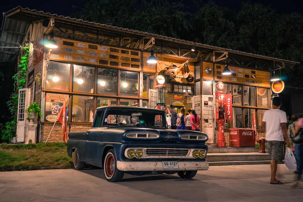 Eine Reihe alter Fahrzeuge und Roller vor Lagerhäusern – versinnbildlicht die reiche Historie, wie sie sich auch in der Entwicklung von Fanta in Deutschland widerspiegelt.