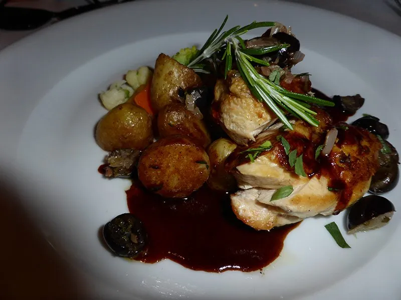 Eine saftige Maispoulardenbrust mit Oliven, Schalotten, Limette und Estragon, serviert mit knusprigen Bratkartoffeln und einer aromatischen Jus.