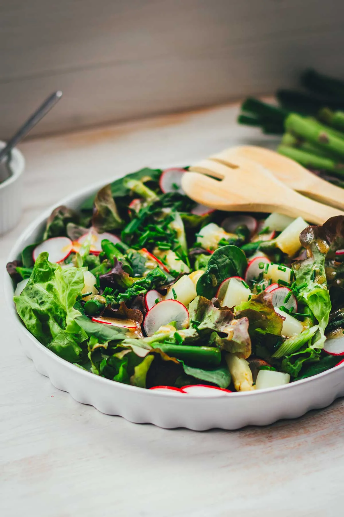 Eine Schale mit Blattsalaten, Radieschen und blanchiertem grünem Spargel, bereit zum Mischen.