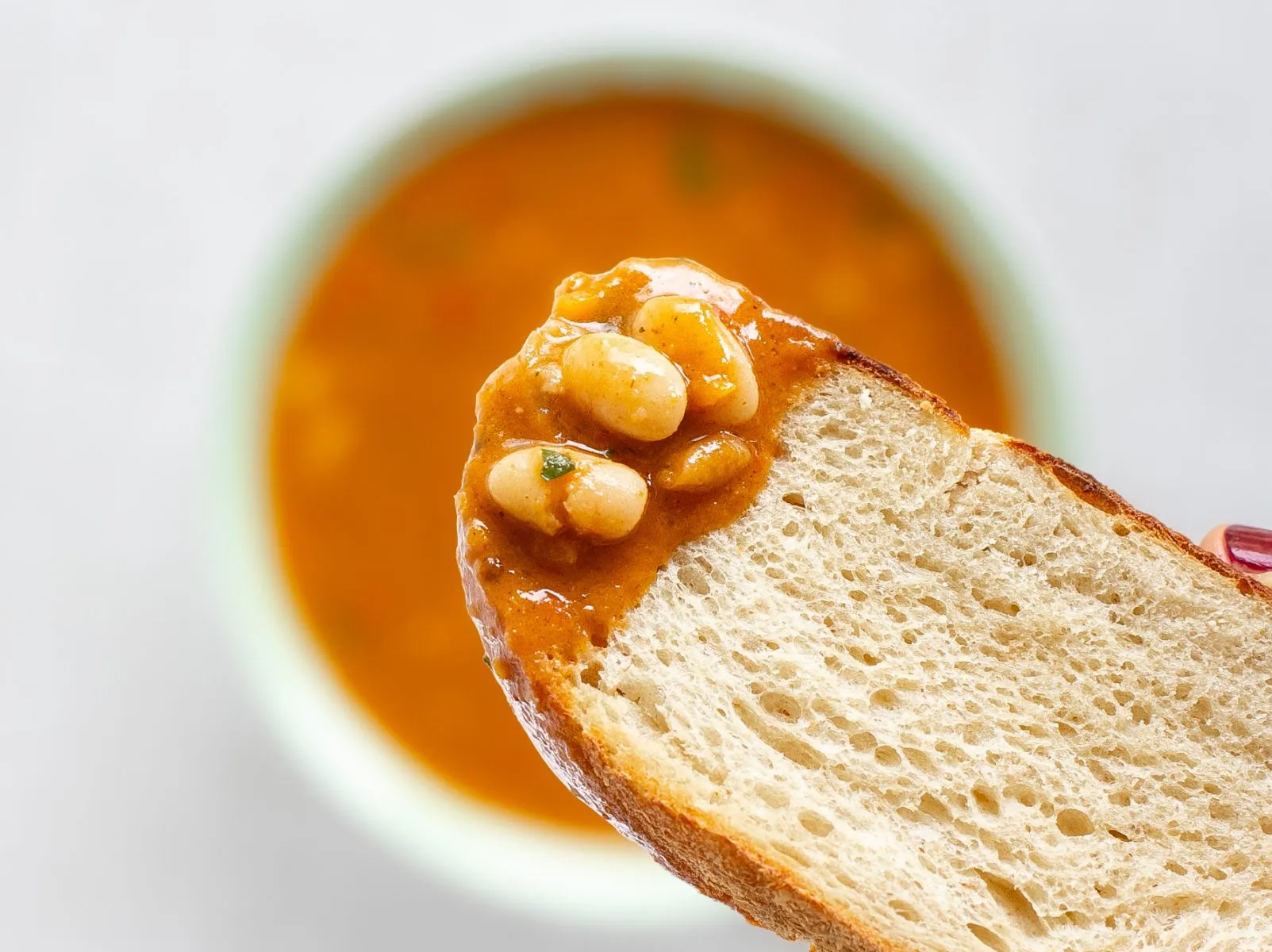 Eine Scheibe gutes Brot, perfekt zum Eintunken in die herzhafte vegane Bohnensuppe.